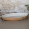 Oval ceramic dish with terracotta rim on a neutral background