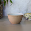 Brown ceramic bowl on a light surface with a blurred background