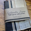 Folded apron with plaid pattern on a wooden surface, labeled 'Grillmaster Apron'.