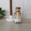 Glass jar with matches and a label on a neutral background