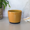 Yellow ceramic pot on a white surface with a blurred background