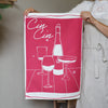 Person holding a pink towel with white wine graphics and 'Cin Cin' text.