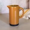 Orange ceramic pitcher on a neutral background