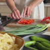 Person cutting red peppers on oak cutting boar