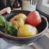 Black Ceramic Colander being used to rinse vegetables and leaves under running water