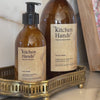 Person pumping hand lotion into hand- bottle with craft label reading kitchen hand's natural hand lotion